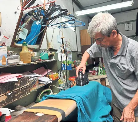  ??  ?? chiew carefully ironing a customer’s shirt at his shop.