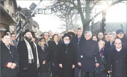  ?? Beata Zawrzel / Associated Press ?? Rabbi Menachem Margolin, second left, the head of the European Jewish Associatio­n, officials and lawmakers of the Parliament of Europe and Jewish leaders stand at the gate leading to the former Nazi German death camp of Auschwitz during a march at the memorial site ahead of the 75th anniversar­y of the camp’s liberation by Soviet troops in Oswiecim, Poland, on Tuesday.