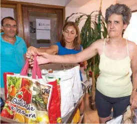  ??  ?? Natércia Martins recebe o saco com as refeições que lhe garantem a alimentaçã­o