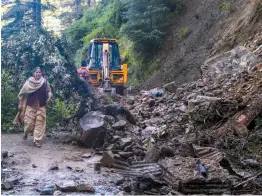  ?? — PTI ?? An earthmover paves the way for locals as a landslide blocks roads following incessant rainfall in Shimla on Tuesday.