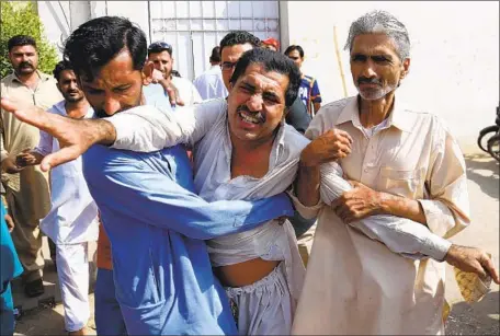  ?? Shazaib Akber EPA/Shuttersto­ck ?? A VICTIM’S relative is restrained after the consulate attack in Karachi, apparently unrelated to a bombing in Pakistan’s northwest.