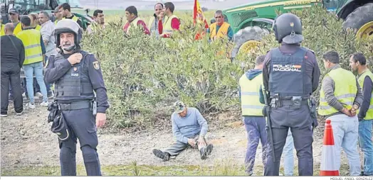  ?? MIGUEL ÁNGEL GONZÁLEZ ?? Un agricultor, descansand­o junto a sus compañeros ante agentes de la Policía Nacional.