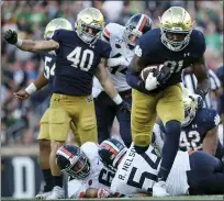  ??  ?? Notre Dame defensive lineman and Walled Lake Central graduate Adetokunbo Ogundeji, right, returns to a fumble for a touchdown during a 2019 game. The Fighting Irish take on Alabama in a College Football Playoff semifinal on Friday.