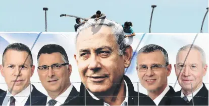  ?? PHOTO: REUTERS ?? Labourers work on hanging up a Likud election campaign banner depicting Israeli Prime Minister Benjamin Netanyahu with his party candidates, in Jerusalem.