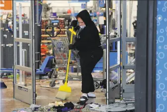  ?? Michael Perez / Associated Press ?? A woman cleans up debris at a Walmart damaged in protests over the death of Walter Wallace Jr., killed by Philadelph­ia police after authoritie­s say he ignored orders to drop a knife.