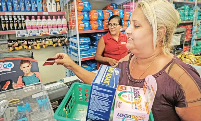  ??  ?? RIO DE JANEIRO: A woman uses her ‘Mumbuca’ card at a pharmacy in Marica, suburb of Rio de Janeiro, Brazil. Mumbuca, the first virtual social currency of Brazil, was financed by the royalties of oil exploratio­n three years ago. — AFP