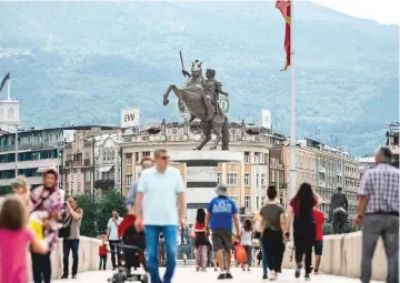  ??  ?? People crossing the old bridge of the Vardar river in front of the monument of King Alexander the Great in the centre of Skopje.