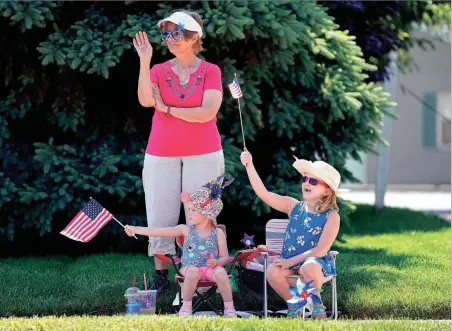  ?? KYLE ROBERTSON/ COLUMBUS DISPATCH ?? ABOVE: Sue Grace along with granddaugh­ters Laurie, 6, and Vivian, 2, wave to members of American Legion Post 164 during the Grove City Memorial Day parade in 2022. Memorial Day honors those in the military who died in service to the nation. The day is marked by parades, procession­s and solemn tributes at cemeteries.