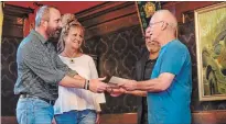  ?? GARY YOKOYAMA THE HAMILTON SPECTATOR ?? Dean McCoy, left, manager of Value Village, and employee Karen Davis, who found the letter, present it to Don McIsaac Jr. (son of Pte. Don McIsaac), who accepts it with his son Dale McIsaac.
