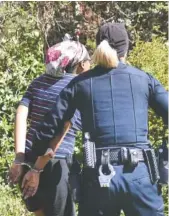  ??  ?? Lt. Heather Williams leads a woman in handcuffs Wednesday on Bennett Avenue.