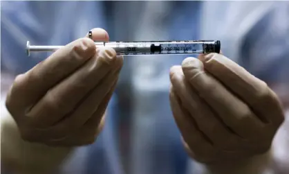  ??  ?? A pharmacy technician holds a dose of the Johnson & Johnson Covid-19 vaccine before it is administer­ed in a clinical trial. Photograph: Michael Ciaglo/Getty Images