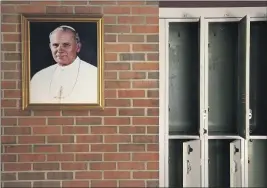  ?? JESSIE WARDARSKI – THE ASSOCIATED PRESS FILE PHOTO ?? In this file photo from June 8, a portrait of St. John Paul II hangs beside a row of empty lockers in the main hallway of Quigley Catholic High School in Baden, Pa. On Feb. 8, Catholic education officials reported that enrollment in Roman Catholic schools in the United States dropped 6.4% from the previous academic year amid the pandemic and economic stresses — the largest single-year decline in at least five decades.