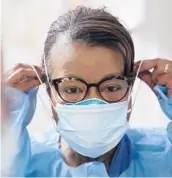  ?? ELAINE THOMPSON/AP 2020 ?? A respirator­y therapist pulls on a second mask over her
N95 mask as she gets ready to go into a patient’s room at a Seattle hospital.