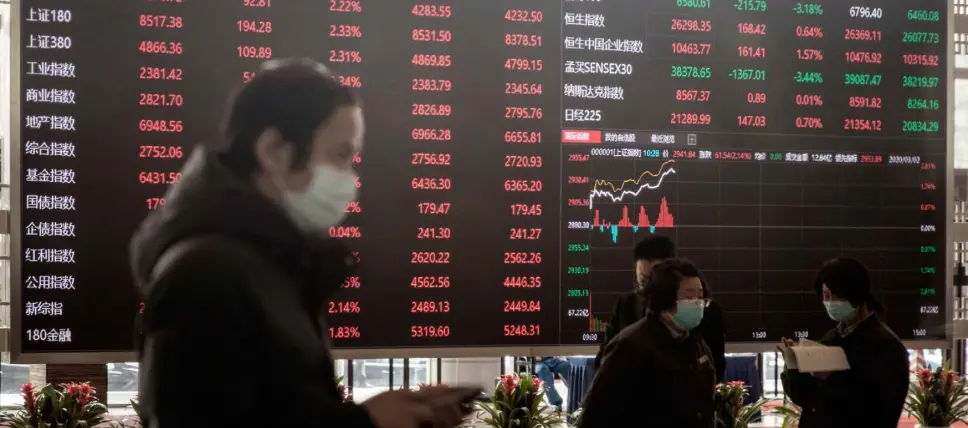  ??  ?? Employees and visitors wearing protective masks walk past an electronic stock board at the Shanghai Stock Exchange in Shanghai, China