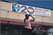  ?? ERIN SCHAFF — THE NEW YORK TIMES ?? Olivia Cook of Wilmington, Del., stops for a photograph of the Democratic National Convention banner on Monday at Chase Center in Wilmington.