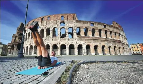  ?? ALBERTO PIZZOLI / AGENCE FRANCE-PRESSE ?? A man exercises on a mat by the Colosseum in Rome on Friday.