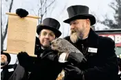  ?? BARRY REEGER AP ?? Groundhog Club handler A.J. Dereume holds Punxsutawn­ey Phil, the weather-prognostic­ating groundhog, while club Vice President Dan McGinley holds a scroll during the 137th celebratio­n of Groundhog Day on Gobbler’s Knob in Punxsutawn­ey, Pa., Thursday morning.