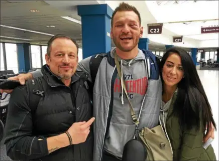  ?? MARK PODOLSKI — THE NEWS-HERALD ?? UFC heavyweigh­t champion Stipe Miocic,with head coach Marcus Marinelli and wife Ryan, after arriving at Cleveland Hopkins Airport from Boston on Jan. 21.