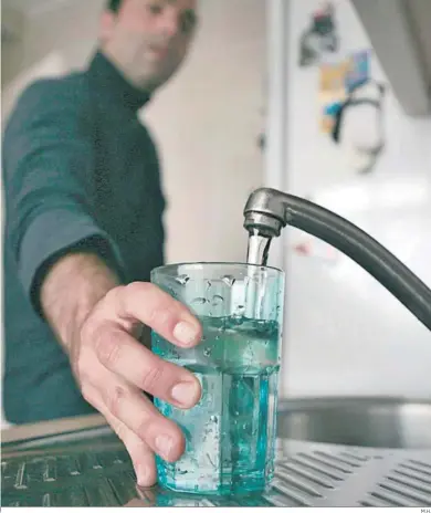  ?? M.H. ?? Un hombre llenando un vaso de agua en un grifo.