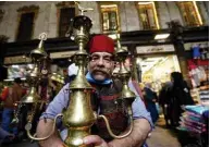  ??  ?? Ishaaq Kremed, poses for a picture with his ornate brass jug in the covered Hamidiyah market.