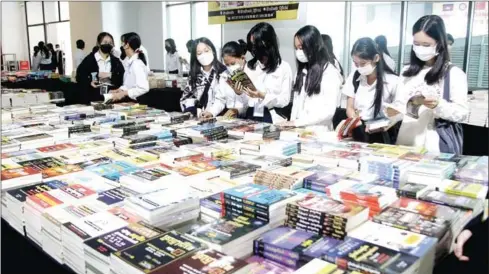  ?? HENG CHIVOAN ?? Dozens of female students examine volumes of Khmer literature at a Phnom Penh book fair in February last year.