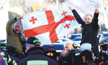  ?? VANO SHLAMOV AFP VIA GETTY IMAGES ?? Georgian opposition supporters hold a national flag during a rally following the arrest of lawmaker Nika Melia in Tbilisi on Tuesday.