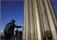  ?? AP/The El Paso Times/MARK LAMBIE ?? Visitors touch the 30-foot-tall golden obelisk unveiled Saturday in the Walmart parking lot where 22 people were killed this summer in El Paso, Texas.