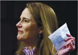 ?? PHOTO BY SAMUEL CORUM — GETTY IMAGES ?? Supreme Court nominee Amy Coney Barrett holds a face mask up as she testifies during the third day of her confirmati­on hearings before the Senate Judiciary Committee on Capitol Hill in Washington, Wednesday.