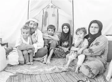  ??  ?? A handout picture released by Save The Children shows Syrian siblings Yacoub (centre, left), 12, and Faridah (centre, right), 13, from Raqqa, sitting with their parents inside a tent in which they live, in a camp for people displaced by the war against...