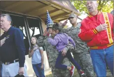  ?? NEWS-SENTINEL PHOTOGRAPH­S BY BEA AHBECK ?? Marina Montes, Army Master Sgt., holds daughter, Viviana, 5, as she and her husband, Carlos Montes, Chief Warrant Officer, salute during the “Pledge of Allegiance,” at Vinewood Elementary School in Lodi on Friday.