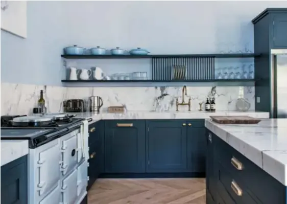  ??  ?? NOUVELLE CUISINE Marmorplat­te und Tellerbord verleihen der dunkelblau­en Küche die elegante Leichtigke­it.