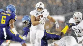  ?? TIM TAI / PHILADELPH­IA DAILY NEWS ?? Army running back Darnell Woolfolk runs the ball through falling snow during the annual Army-Navy game Saturday in Philadelph­ia.