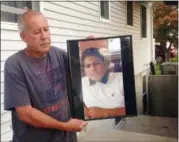  ?? CLAUDIA TORRENS — THE ASSOCIATED PRESS ?? In this Sept. 27 photo, Abraham Chaparro holds a photograph of his murdered stepson, Miguel GarciaMora­n, outside his home in Brentwood. The remains of Garcia-Moran, who was reported missing in February, were found in September. Multiple teenagers from...