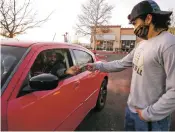  ?? MATT DAHLSEID/THE NEW MEXICAN ?? Zach Martinez, a football player and junior at Santa Fe High, accepts a cash donation from Njolai Abdelaziz on Tuesday in the parking lot of Regal Santa Fe theater.