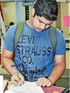  ??  ?? Muhammad Usman, 16, a junior, fills out paperwork during Moore High School’s first day of classes for the 2017-18 school year.