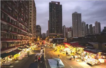  ??  ?? Fruit vendors work on a main road at the wholesale Yau Ma Tei fruit market. — AFP photos by Anthony Wallace