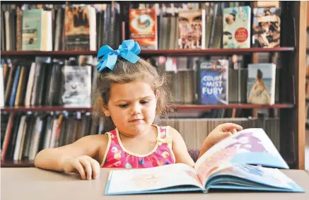  ?? STAFF PHOTO BY ANGELA LEWIS FOSTER ?? Lyla Silecchia looks at a book Thursday at the Rossville Public Library. The library will move to a temporary location at the Rossville Athletic Center while the current building is renovated.