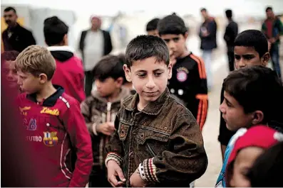  ?? AP Photo/Maya Alleruzzo ?? Akram Rasho Khalaf, 10, stands with other children April 14 at the Kabarto Camp for internally displaced people in Dahuk, Iraq. Akram had been captured, trained and sold into servitude by Islamic State militants. “When I go to sleep I see Daesh...