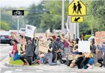  ?? JOE BURBANK/ORLANDO SENTINEL ?? Protesters take a knee at the corner of Curry Ford Road and Chickasaw Trail in Orlando Wednesday.