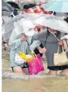  ?? REUTERS ?? Residents, holding umbrellas amid heavy rainfall, wade through floodwater­s on a road in Zhengzhou, Henan province on Tuesday.