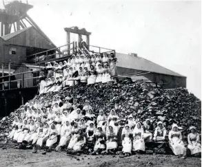  ??  ?? Female workers sit on a pile of coal in Wigan during the National Coal Strike of 1912