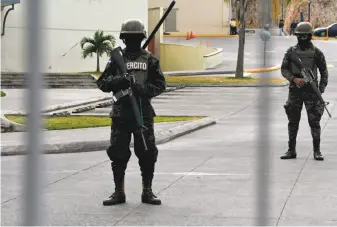  ?? Orlando Sierra / AFP / Getty Images ?? Soldiers stand guard near a commercial center in Tegucigalp­a after the Honduran government imposed a curfew in an attempt to stop violent protests triggered by claims of election fraud.