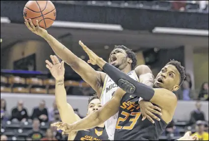  ?? MICHAEL CONROY / ASSOCIATED PRESS ?? Derrick Walton Jr. gets fouled by Oklahoma State’s Leyton Hammonds while driving to the hoop during Michigan’s 92-91 victory. Walton finished with 26 points and 11 assists.