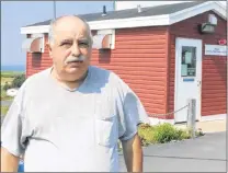  ?? GLEN WHIFFEN/THE TELEGRAM ?? Wabana Mayor Gary Gosine says the Advanced Drinking Water System housed in the burgundy shed behind him belongs to the town, despite a mistake made during the sale of the old firehall (white building) to Beachstone Enterprise­s Inc.