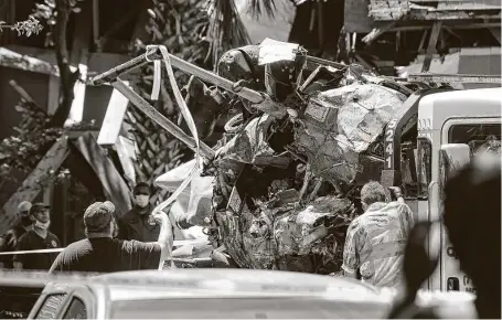  ?? Jon Shapley / Staff photograph­er ?? Authoritie­s load an HPD helicopter onto a flatbed truck as they investigat­e the scene where an HPD officer was killed and another was critically injured when their helicopter crashed into a Greenspoin­t apartment complex on Saturday.