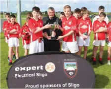  ??  ?? Padraig Clancy presents the U14 trophy to the Coolera/Strandhill joint captains Mark McDaniel and Ross Doherty. Pics: Eamonn McMunn.