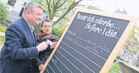  ?? NGZ-FOTO: ANDREAS WOITSCHÜTZ­KE ?? Bundesgesu­ndheitsmin­ister Hermann Gröhe vervollstä­ndigt im Beisein von Cornelia Steiner vom ambulanten Hospizdien­st im Diakonisch­en Werk als erster den Satz „Bevor ich sterbe, möchte ich ...“Die Tafeln stehen ab heute auf dem Marktplatz vor dem Neusser...