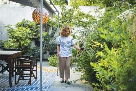  ?? AFP ?? The ‘hard hit’ American home-sharing platform announced on Tuesday that it will slash a quarter of its work force — some 1,900 people all around the world.
Romina Tsitou, owner of two homes in Greece’s Koukaki district available on Airbnb, waters plants at one of them during a lockdown in Athens.