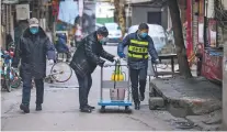  ?? CHINATOPIX VIA AP ?? Government workers spray disinfecta­nt Tuesday in Wuhan, China.