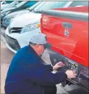  ?? Mick Akers Las Vegas-review Journal ?? Boulder City resident Tony Cloud attaches his newly acquired Raiders Nevada specialty license plate to his pickup truck on Monday, the first day of its availabili­ty.